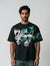 Man wearing a black t-shirt with green and white graphics on a plain background