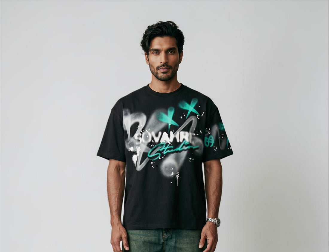 Man wearing a black t-shirt with green and white graphics on a plain background
