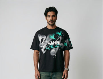 Man wearing a black t-shirt with green and white graphics on a plain background